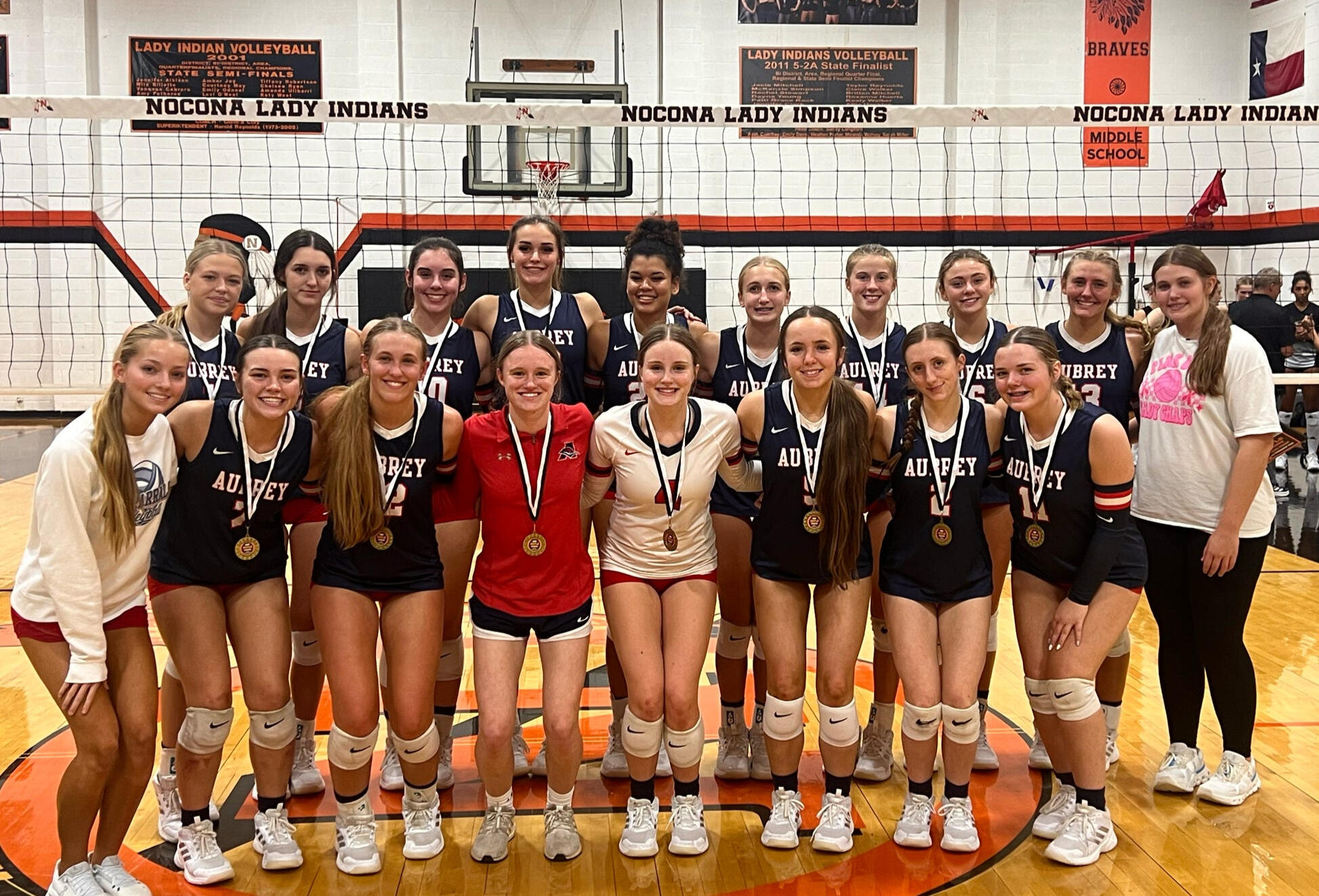 2025 Aubrey Lady Chaps | Nocona Tournament Champions The 2025 Aubrey Lady Chaps Volleyball Team Standing on a Volleyball Court After Winning the Nocona Tournament